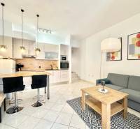 Ferienwohnung mit Kochnische, Esstisch, Sofa und Kunstgemälden an der Wand.