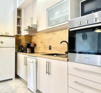 Küche in der Ferienwohnung mit weißen Möbeln und Holzwanddekor.