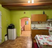 Küche in einem Einfamilienhaus mit grünen Wänden, einem Blumen-Tischtuch und Holzboden-Dekor.