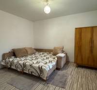 Schlafzimmer eines Einfamilienhauses mit Bett, Kleiderschrank und Boden in Holzoptik.