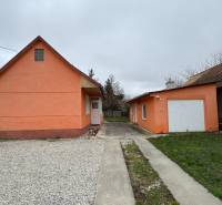 Ein Einfamilienhaus in Čechynce mit einer orangefarbenen Fassade, einem Betonweg und einer Garage.