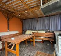 Hinter dem Einfamilienhaus in Čechynce befindet sich eine überdachte Terrasse mit Sitzgelegenheiten und einer orangefarbenen Wand.