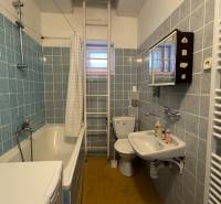 Ein Badezimmer in einem Einfamilienhaus mit einer Badewanne, einer Waschmaschine und blauen Fliesen.