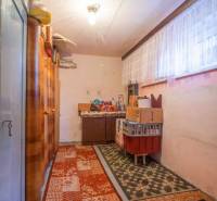 Úložný priestor v rodinnom dome s kobercami, policami a krabicami.