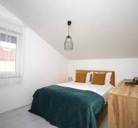 Schlafzimmer im Ferienapartment mit Doppelbett, Fenster und Kommode unter dem schrägen Dach.