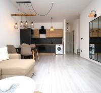 Wohnzimmer der Ferienwohnung mit Küche, Tisch, Spiegel und Holzboden.