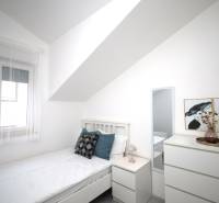 Helles Schlafzimmer in einer Ferienwohnung mit Bett, Nachttisch und Kommode.