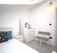 Ferienwohnung mit hellem Schlafzimmer, Bett, Kommode und Kissen, Boden mit Holzdekor.