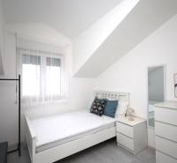 Helles Zimmer mit Bett, Spiegel und Dekorationen in einer Ferienwohnung.