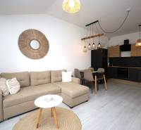 Wohnzimmer in einer Ferienwohnung mit Küche, Sofa und dekorativen Elementen an der Wand.