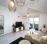 Wohnzimmer im Ferienapartment mit bequemer Couch, TV und Balkon.