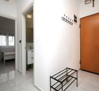 Ferienwohnung mit Fliesenboden, Garderobe, offenen Türen zum Schlafzimmer und Badezimmer.