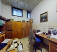 Ein Büro mit Holzschränken, einem Schreibtisch und Regalen, mit Fliesen im geometrischen Muster.