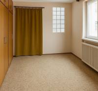 Ein Zimmer in einem Einfamilienhaus mit Teppichboden, Einbauschrank und Vorhang.