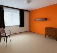 Ein Zimmer mit einer orangefarbenen Wand, Möbeln, einem Fenster und einem Teppichboden in einem Einfamilienhaus.