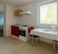 Küche mit rotem Schrank, Tisch und zwei Stühlen in einem Einfamilienhaus.