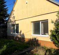 Ein Einfamilienhaus in Diakovce mit einem schrägen Dach und einer gelben Fassade, umgeben von Grün.