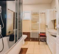 Badezimmer in einem Einfamilienhaus mit Badewanne, Dusche, Waschbecken und Heizkörper.