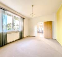 Ein Zimmer mit einem großen Fenster, einem Heizkörper und einem Durchgang in einem Einfamilienhaus.