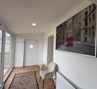 Innenraum einer Einzimmerwohnung mit Holzboden, Glastüren und Kunst an der Wand.