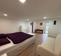 Ein Schlafzimmer in einer Einzimmerwohnung mit Holzboden, einfache Möbel und Dekorationen.