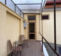 Überdachte Terrasse mit zwei Stühlen und einem Tisch vor dem Eingang zu einem Einzimmerapartment.