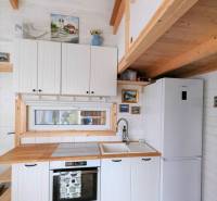 Küche im Einfamilienhaus mit weißen Schränken, Holzelementen und bunten Fliesen.