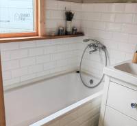 Ein Badezimmer in einem Einfamilienhaus mit eingebauter Badewanne und weißen Fliesen.