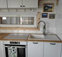 Küchenzeile im Einfamilienhaus mit weißen Schränken, Spüle und eingebautem Backofen.