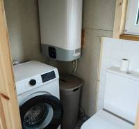 Badezimmer in einem Einfamilienhaus mit Waschmaschine, Boiler und Toilette. Der Boden hat dekorative Fliesen.