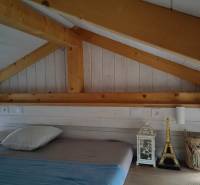 Ein Dachbodenschlafzimmer in einem Einfamilienhaus mit Holzdecke und Dekorationen neben dem Bett.