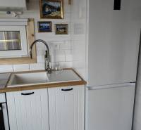 Küche im Einfamilienhaus mit weißer Küchenzeile, Kühlschrank und Kunstbildern an der Wand.