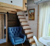 Innenraum eines Einfamilienhauses mit blauem Sessel, Holztreppe und Boden mit Holzdekor.