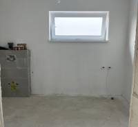 Ein leerer Raum in einem Einfamilienhaus mit Holzelementen und einem schmalen Fenster an der Wand.