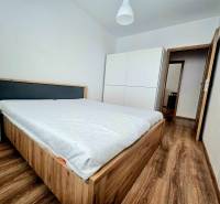 Schlafzimmer in einer 2-Zimmer-Wohnung mit Holzboden, Bett und weißem Schrank.