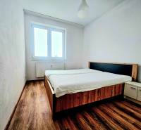 Schlafzimmer in einer 2-Zimmer-Wohnung mit Holzboden, Bett und Fenster.