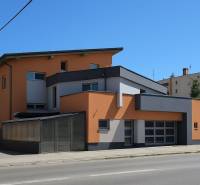 Ein Gebäude in Šaľa mit modernem Design, orange-grauer Fassade und großen Fenstern.