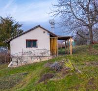 Ein Ferienhaus in Prešov, umgeben von Obstbäumen und üppigem Grün auf einem Hanggrundstück.