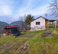 Eine Hütte in Prešov, umgeben von Bäumen, mit Blick auf die Hügel und einem Trampolin im Garten.