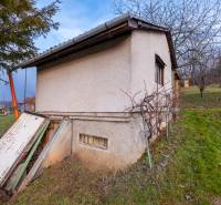 Eine Hütte in Prešov, umgeben von Grün, mit einfachem Putz und einem Außeneingang.