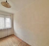 Ein Zimmer in einem Einfamilienhaus mit einem Fenster und einem Vorhang, mit Teppichboden.