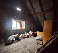 Ein Dachbodenraum mit einem Fenster in einem Einfamilienhaus, voll mit alten Gegenständen und Möbeln.