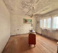 Ein Zimmer in einem Einfamilienhaus mit einfacher Möblierung und einem Boden in Holzoptik.