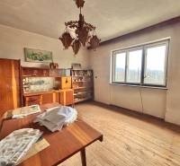 Ein Zimmer in einem Einfamilienhaus mit Holzelementen, Vintage-Möbeln, einem Kronleuchter und einem großen Fenster.