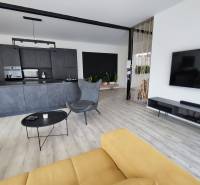 Wohnzimmer mit Küche in einem Einfamilienhaus, Holzboden und gelbes Sofa.