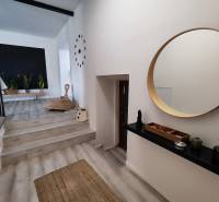 Innenraum eines Einfamilienhauses mit Holzboden, rundem Spiegel und Zimmerpflanzen.