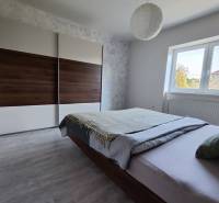 Ein Schlafzimmer in einem Einfamilienhaus mit einem großen Schrank, einem Bett und einem Boden mit Holzdekor.