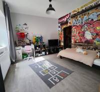 Kinderzimmer im Einfamilienhaus mit Graffiti an der Wand und einem Boden in Holzoptik.