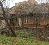 Ein Einfamilienhaus in Komárno mit einem grasbewachsenen Hof, Winterbäumen und älterer Architektur.