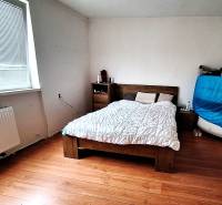 Schlafzimmer im Einfamilienhaus mit Bett, Kommode und Boden mit Holzdekor.